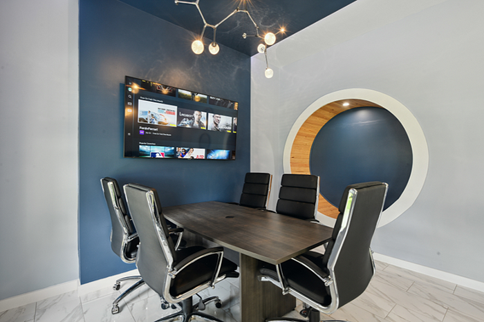 Modern conference room with sleek black chairs, large digital screen, and unique circular wall feature.