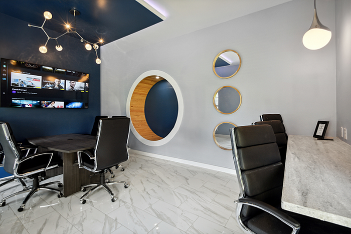 Sophisticated office space featuring modern decor, sleek leather chairs, multimedia setup, and elegant lighting on glossy tiled floors.