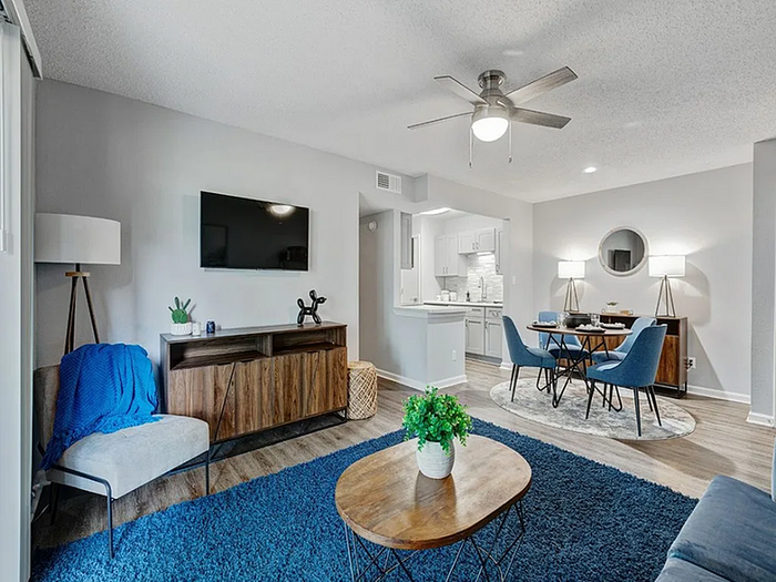 Contemporary living room with stylish decor, featuring a sleek wooden console, modern dining area, and open access to a bright kitchen.
