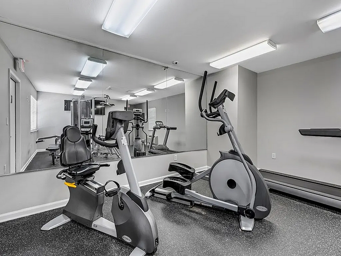 Modern apartment gym with state-of-the-art exercise equipment including a recumbent bike and elliptical, perfect for an active lifestyle.
