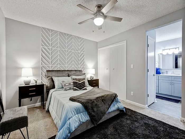 Chic bedroom with modern decor, featuring a cozy bed, stylish geometric accent wall, and adjacent sleek bathroom.