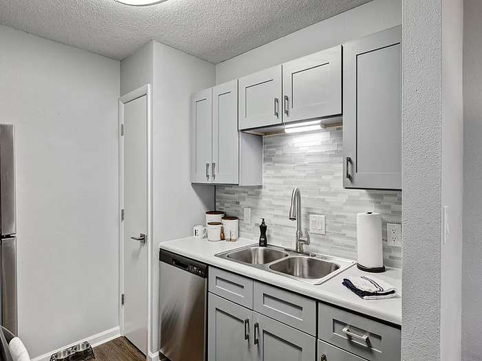 Modern kitchen with sleek gray cabinets, stainless steel appliances, and stylish tile backsplash.