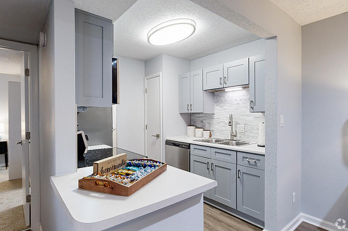 Contemporary kitchen with sleek gray cabinets, modern appliances, and elegant lighting in a cozy apartment setting.