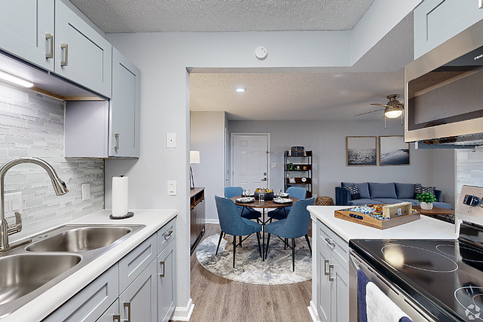 Contemporary open-plan living space featuring a modern kitchen with sleek cabinetry, leading to a chic dining area and inviting living room with stylish decor.