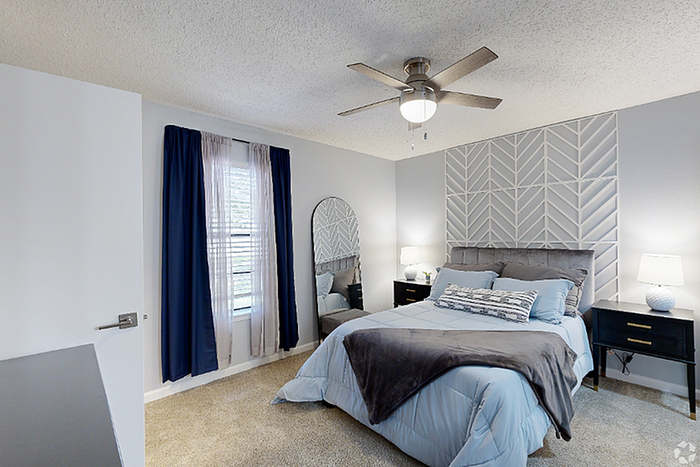 Charming bedroom with a stylish geometric accent wall, cozy bedding, and modern furnishings, bathed in natural light from large windows.