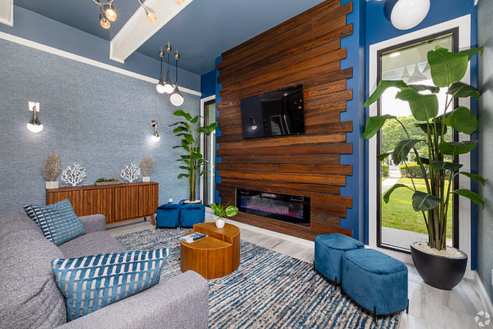 Luxurious living room with modern design, featuring a cozy fireplace, vibrant blue accents, and large windows with garden views.