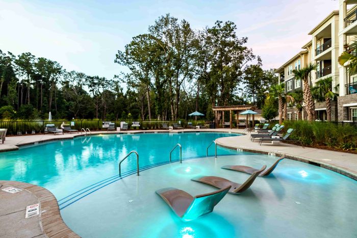 Community swimming pool with lounge chairs and apartment buildings nearby.