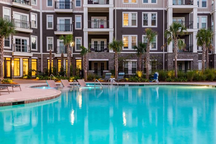 Community swimming pool with lounge chairs and apartment buildings nearby.
