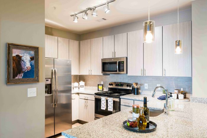 Open kitchen with a white island, stainless steel appliances and dining table.