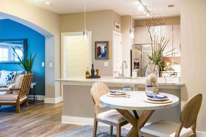 Open kitchen with a white island, stainless steel appliances and dining table.