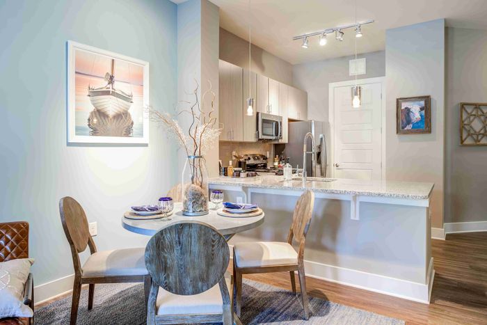 Open kitchen with a white island, stainless steel appliances and dining table.
