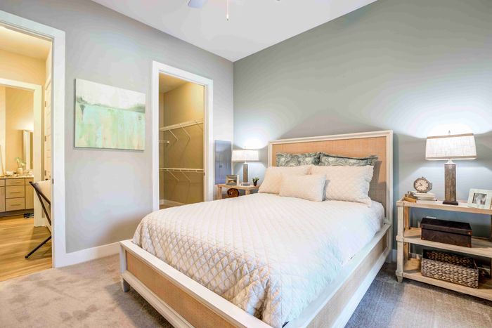 Bedroom with a white bed, blue patterned bedding and a large window.