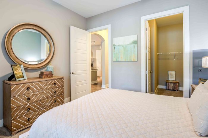 Bedroom with a bed, dresser and open doorway to the bathroom.