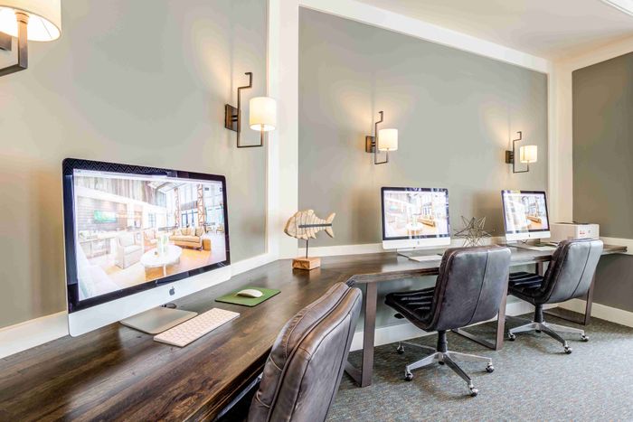 Two computer workstations with monitors, chairs and wall lighting.