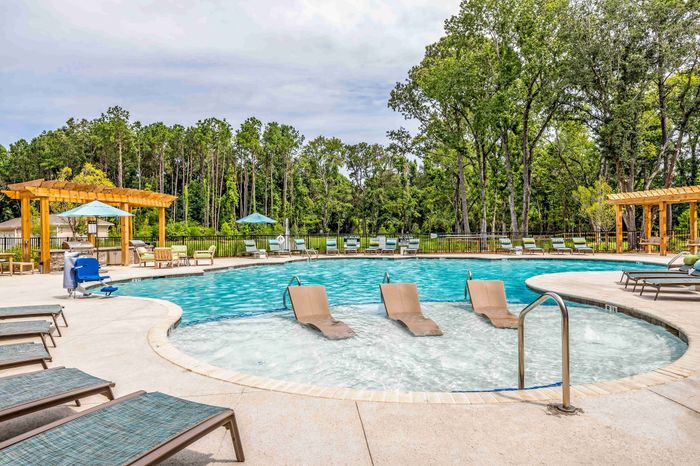 Community swimming pool with lounge chairs and apartment buildings nearby.
