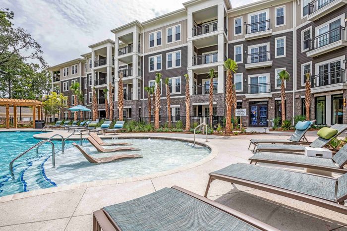 Community swimming pool with lounge chairs and apartment buildings nearby.