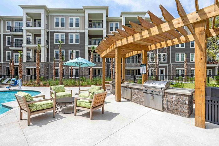 Pergola-covered patio with outdoor seating and a built-in grill.