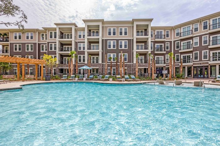 Community swimming pool with lounge chairs and apartment buildings nearby.