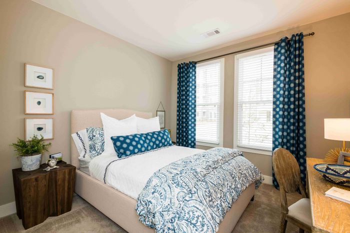 Bedroom with a bed, ceiling fan and large curtained window.