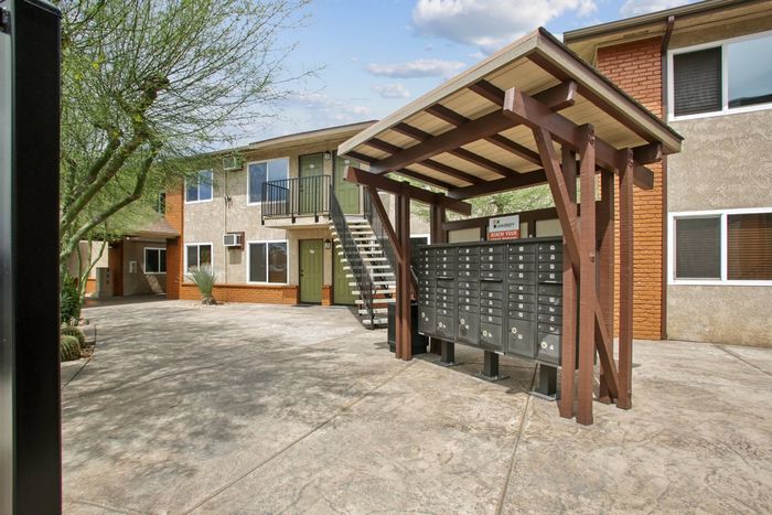 Charming apartment complex exterior with well-maintained landscaping, featuring convenient mailboxes and vibrant greenery.