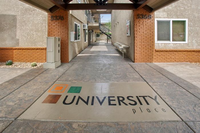 Inviting entryway of University Place with modern aesthetic, featuring textured walls and a welcoming sidewalk.