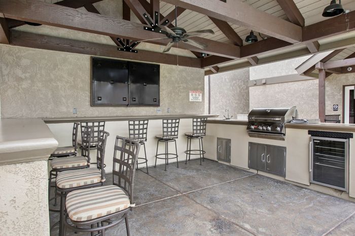 Charming outdoor kitchen with high-top seating, built-in grill, and rustic wood beams.
