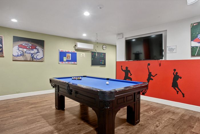 Inviting recreation room featuring a pool table with bright blue felt, hardwood floors, and vibrant basketball-themed decor.