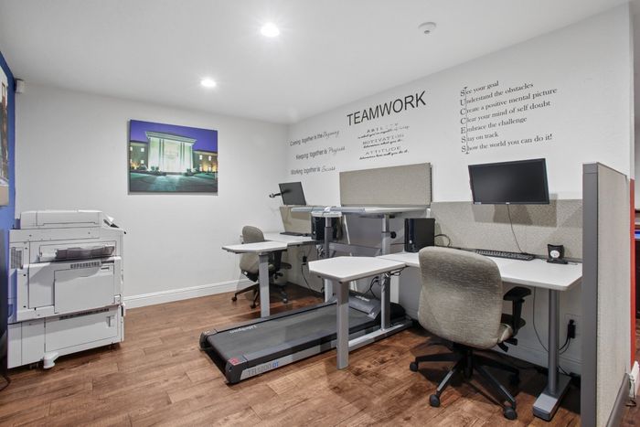 Modern office space featuring adjustable workstations, motivational quotes, and integrated treadmill for an inspiring work environment.