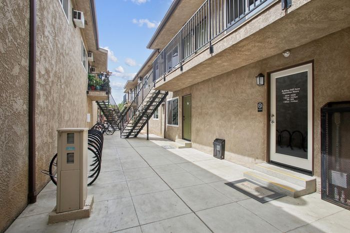 Modern apartment complex with charming stucco exterior and welcoming entry path, featuring convenient outdoor staircase access.