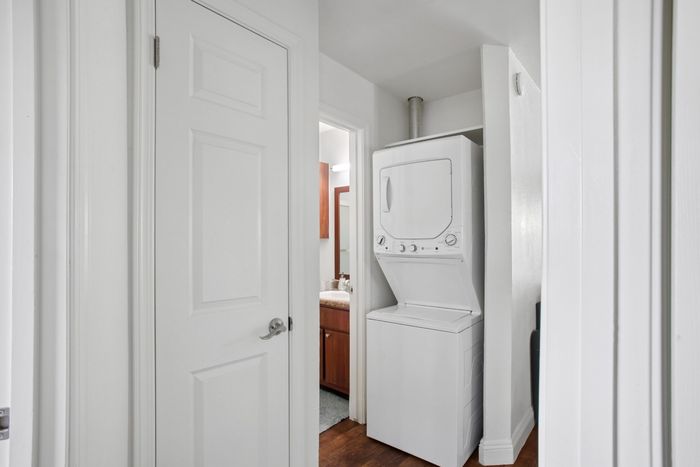 Compact apartment hallway with convenient in-unit stacked washer and dryer near modern bathroom.