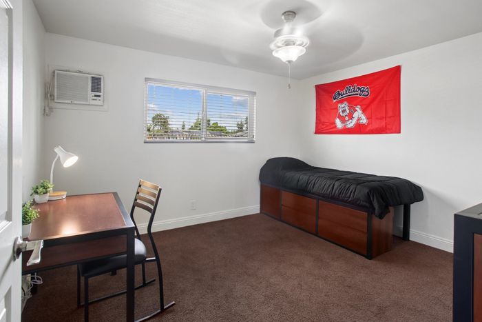 Bright bedroom featuring a sleek desk, comfortable bed, and inspiring decor, perfect for a student or professional.