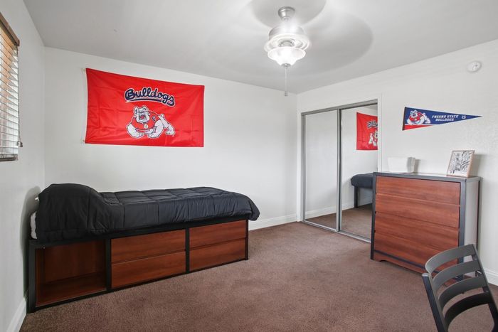 Cozy bedroom with ample storage, featuring a single bed, mirrored closet, and vibrant bulldog-themed decor.