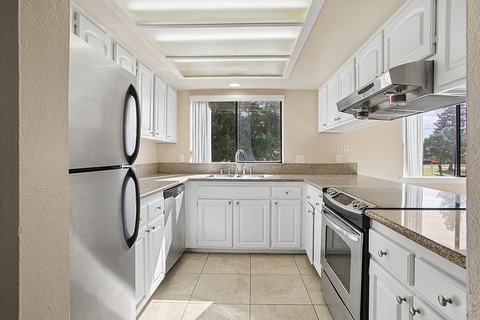 Bright and airy kitchen with modern stainless steel appliances, elegant granite countertops, and ample white cabinetry.