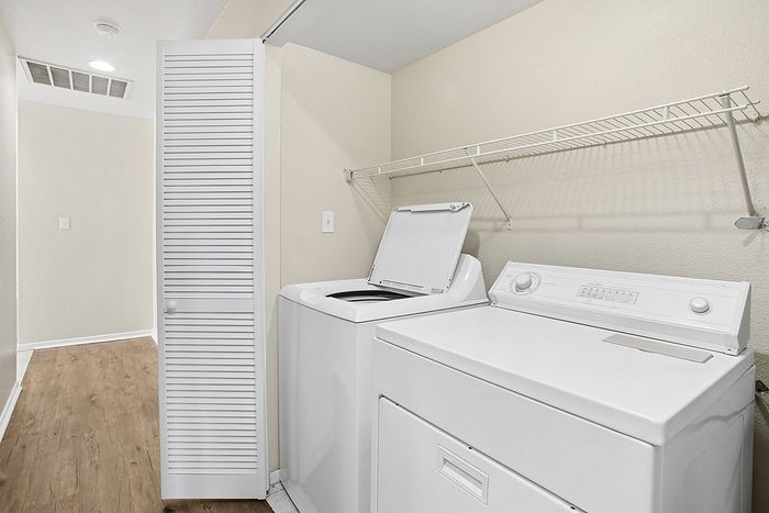 Modern apartment laundry room with washer, dryer, and sleek shelving, showcasing efficient use of space.