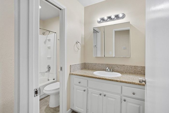 Guest bathroom with granite countertop, sleek vanity, and modern shower in bright, inviting space.