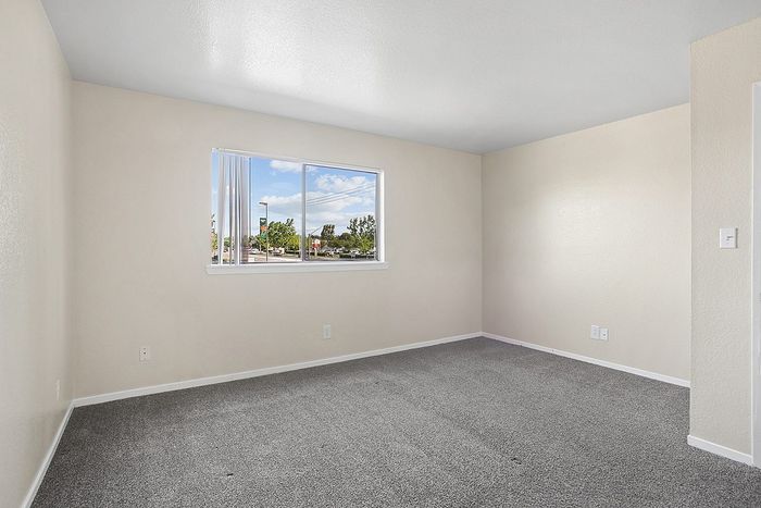 Bright and fresh bedroom with neutral tones and a large window offering scenic outdoor views.
