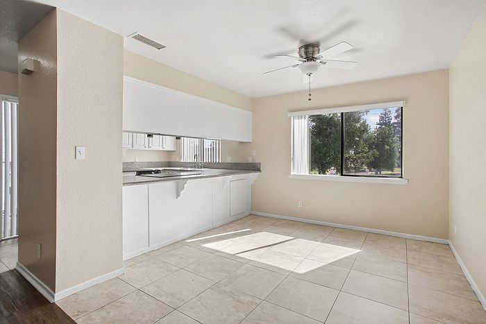 Bright and airy kitchen with modern cabinetry, large window for natural light, and elegant tile flooring.