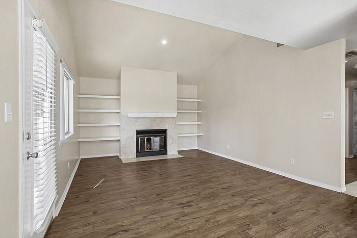 Inviting living room with elegant hardwood floors, modern built-in shelves, and a cozy fireplace, perfect for relaxation.