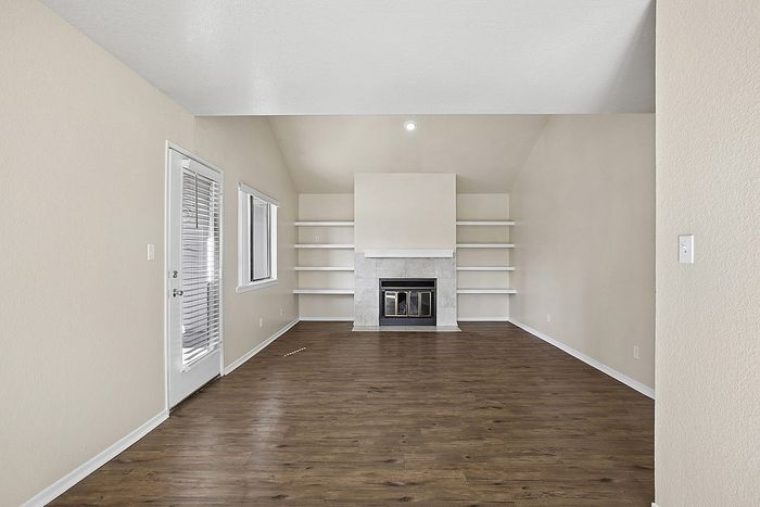 Elegant living room with sleek hardwood floors, a modern fireplace, and built-in shelves, offering a cozy atmosphere.