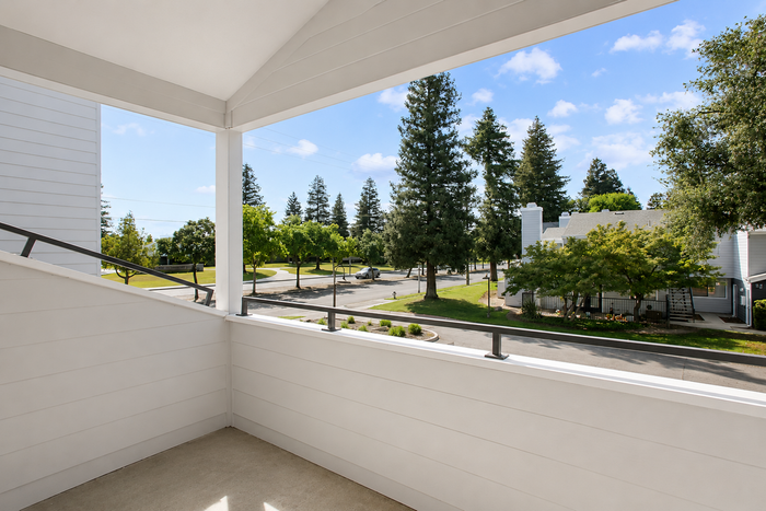 Charming balcony with relaxing views of lush greenery and a peaceful neighborhood setting.
