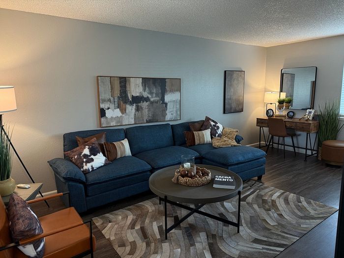 Inviting living room with a stylish blue sofa, modern decor, and a cozy workspace setup, perfect for urban living.
