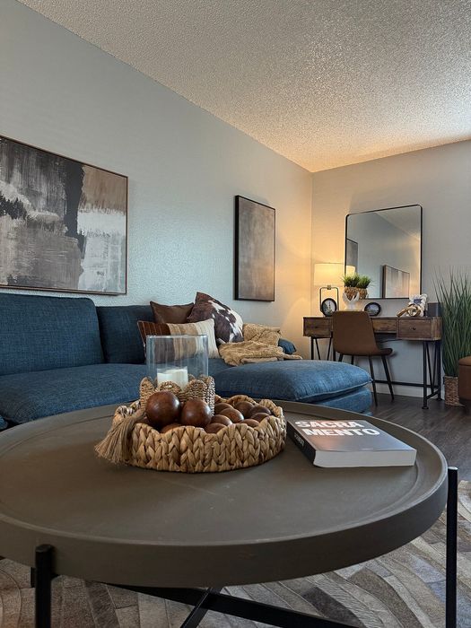 Chic living room with stylish decor, cozy blue sectional, elegant desk, and modern art pieces, ideal for relaxation and productivity.