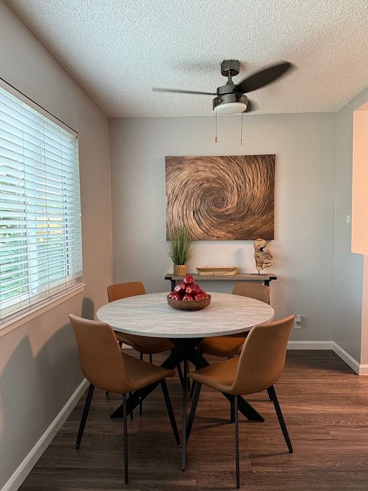 Chic dining area with a modern round table, stylish tan chairs, and an elegant ceiling fan, perfect for intimate gatherings.