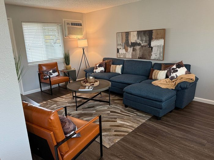 Inviting living room with modern decor, featuring a cozy blue sectional, stylish leather chairs, and elegant artwork.