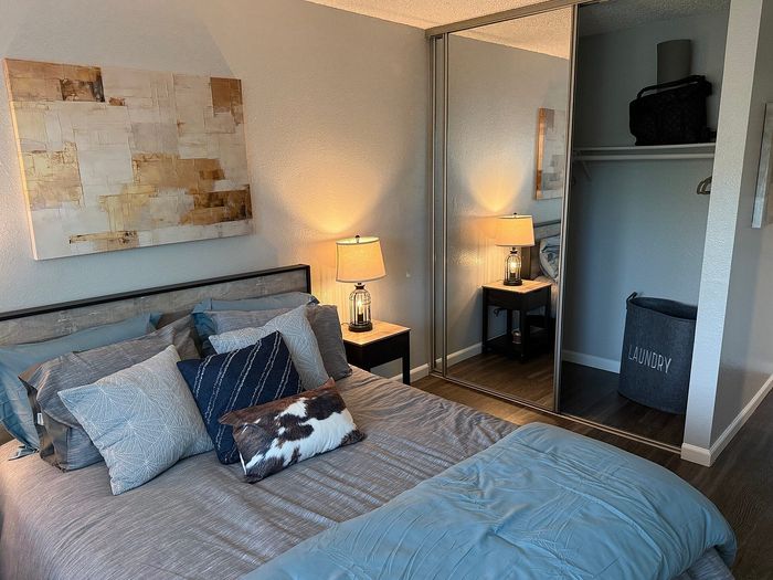 Cozy bedroom with elegant decor, plush bedding, mirrored closet, and soft ambient lighting.