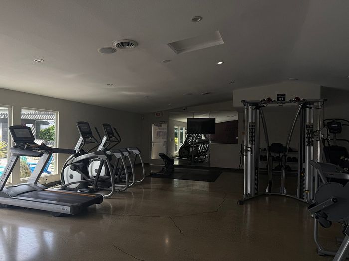 Modern fitness center with state-of-the-art treadmills and multi-station exercise equipment, offering a spacious and bright workout environment.