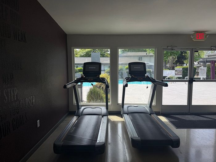 Inviting fitness room with two state-of-the-art treadmills overlooking a refreshing outdoor pool.