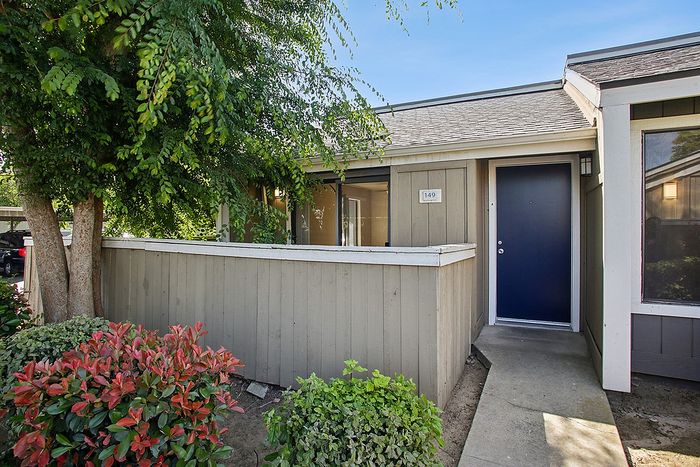 Charming apartment entrance with a cozy patio and lush greenery, perfect for relaxing afternoons.