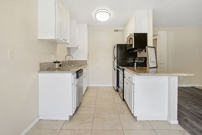 Modern kitchen with sleek white cabinetry, granite countertops, and stainless steel appliances, offering a blend of style and functionality.