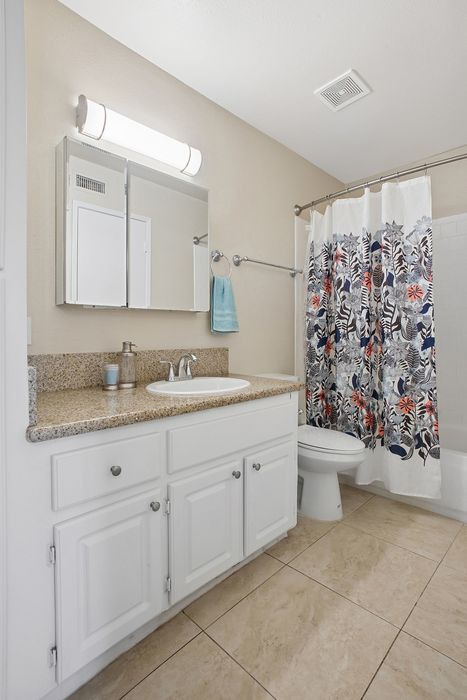 Elegant bathroom with modern fixtures, granite countertop, and stylish floral shower curtain.
